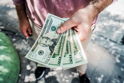 Man holding 20 dollar bills in hand